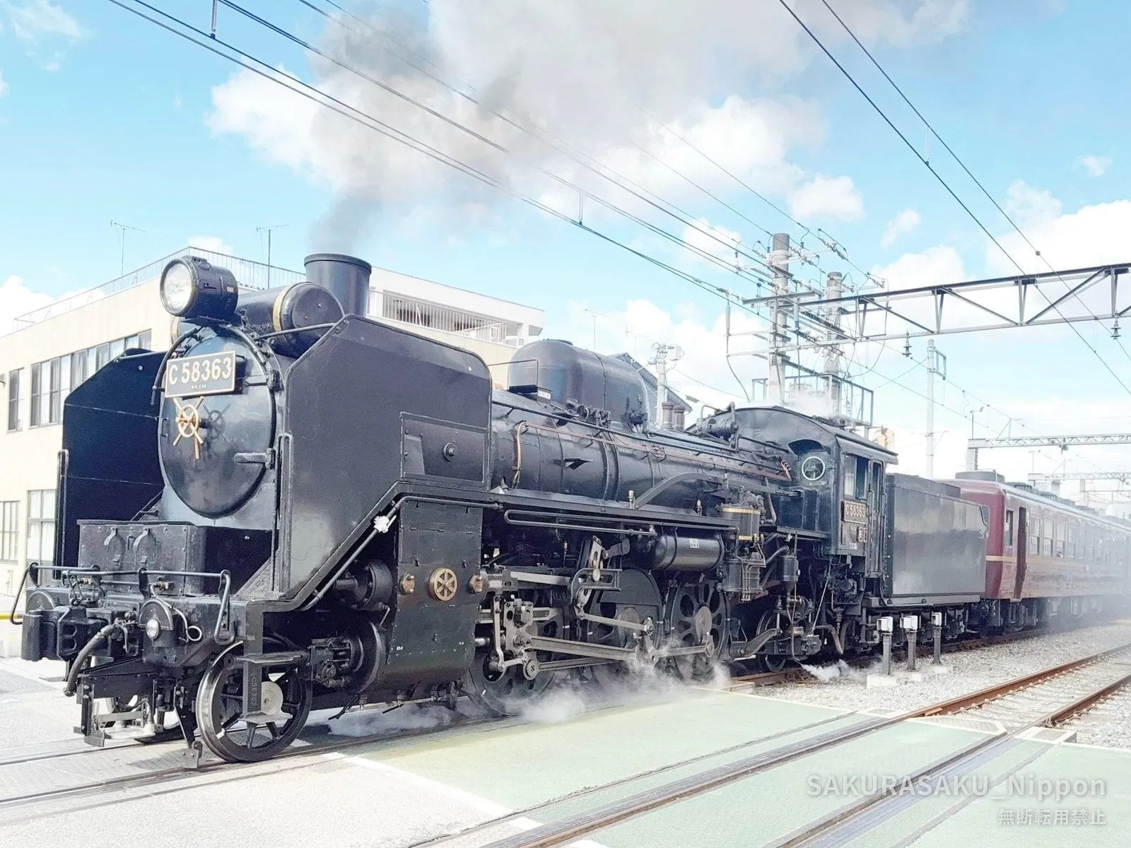 The steam locomotive C58 363 at a platform in Chichibu, steam drifting from its wheels, with maroon coaches behind