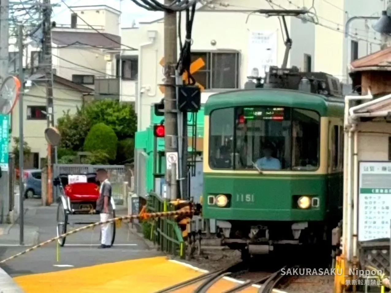 The Enoden train crossing a level crossing in Kamakura, with a rickshaw waiting
